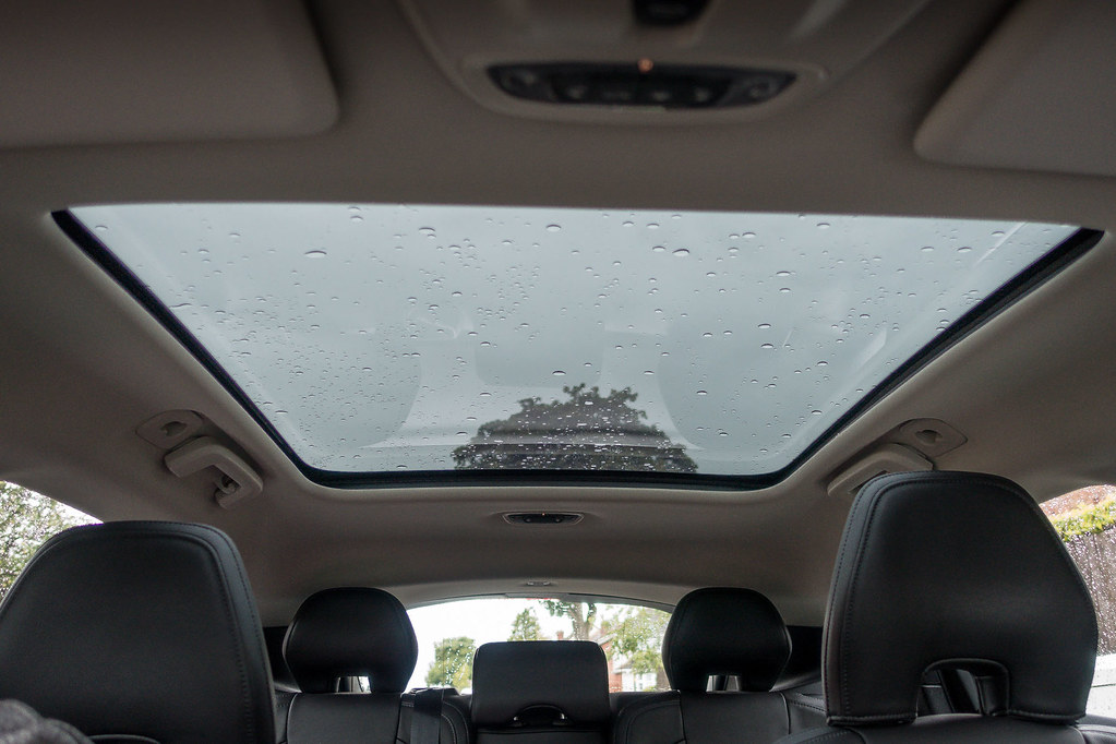 Teto panorâmico visto por dentro do carro, com gotas de chuva no vidro